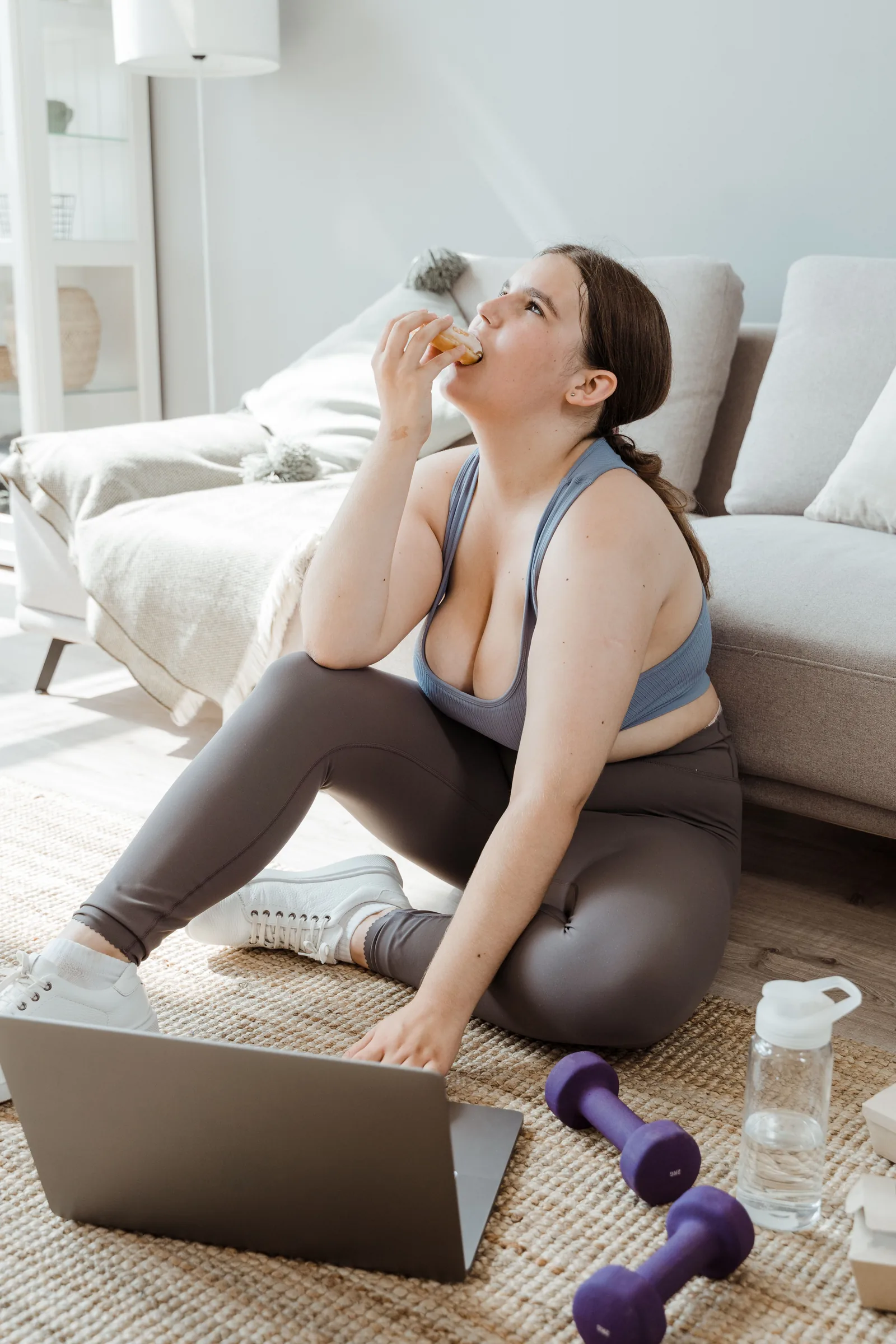 Eating at home beside a laptop and dumbbells